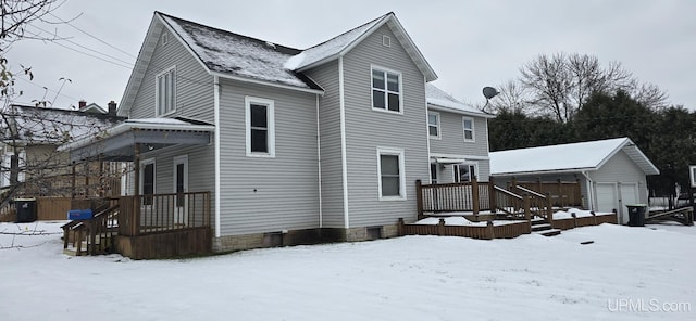 snow covered house with a garage and an outdoor structure