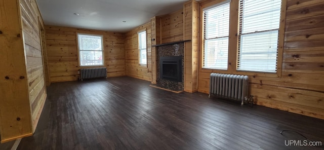 unfurnished living room with radiator, plenty of natural light, and dark hardwood / wood-style floors