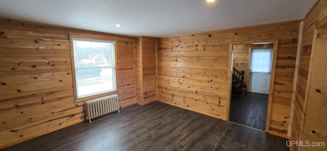 empty room featuring radiator heating unit, a wealth of natural light, and dark wood-type flooring