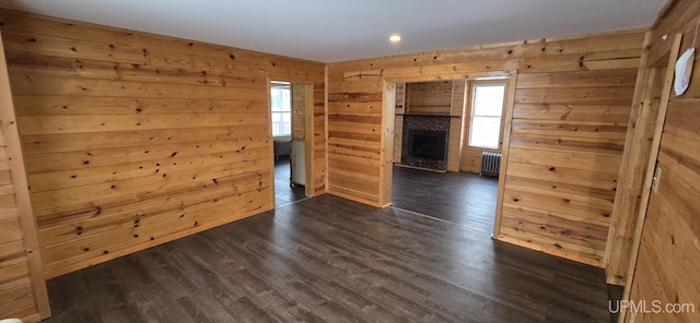 spare room with radiator, dark hardwood / wood-style flooring, a healthy amount of sunlight, and a fireplace