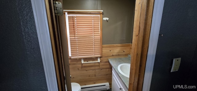 bathroom featuring vanity, toilet, wooden walls, and a baseboard heating unit