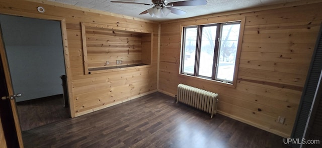 unfurnished room featuring dark hardwood / wood-style flooring, radiator, and wooden walls