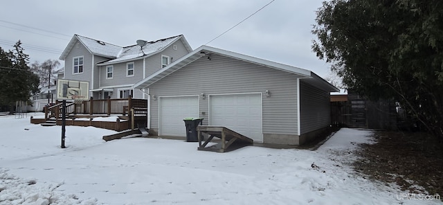 snow covered property with a deck and a garage