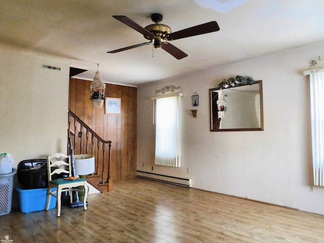 entrance foyer with ceiling fan, wood-type flooring, wooden walls, and a baseboard heating unit