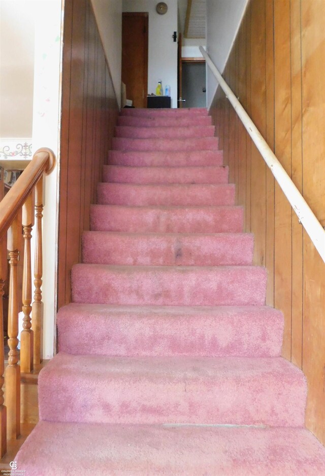 stairway featuring wood walls and wood-type flooring