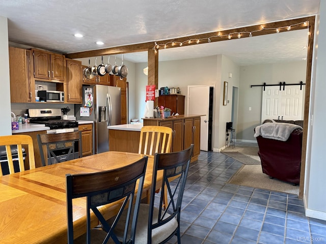 kitchen with dark tile patterned flooring, a barn door, a textured ceiling, and appliances with stainless steel finishes