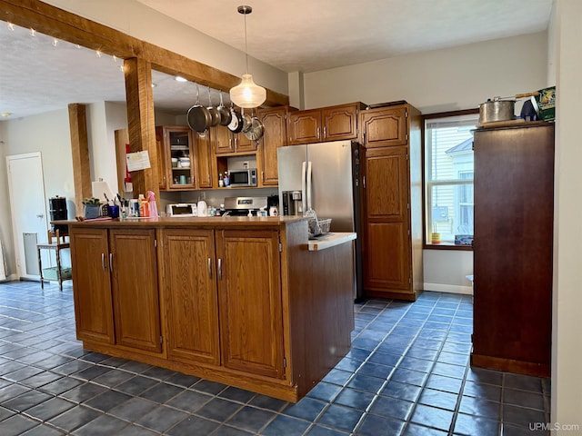 kitchen featuring hanging light fixtures, kitchen peninsula, a textured ceiling, dark tile patterned flooring, and appliances with stainless steel finishes