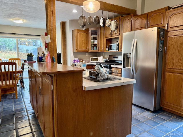 kitchen with pendant lighting, a center island, dark tile patterned flooring, a textured ceiling, and appliances with stainless steel finishes