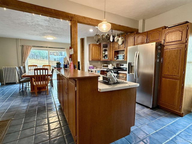 kitchen featuring pendant lighting, a textured ceiling, a kitchen island, radiator heating unit, and stainless steel appliances