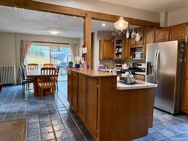 kitchen featuring radiator heating unit, hanging light fixtures, stainless steel appliances, a textured ceiling, and dark tile patterned flooring