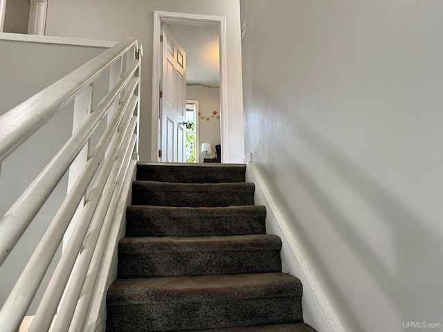 staircase with a textured ceiling