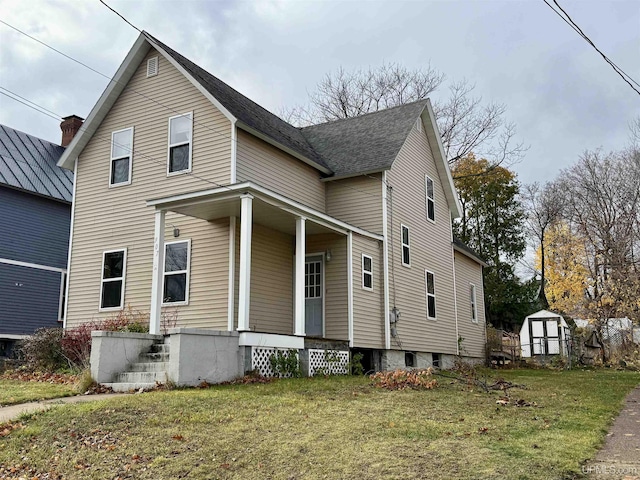 view of front of property featuring a front lawn, a porch, and a storage unit