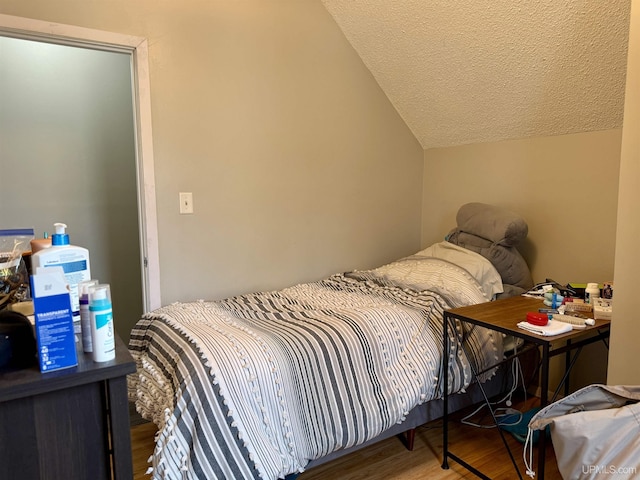 bedroom featuring hardwood / wood-style flooring, a textured ceiling, and vaulted ceiling