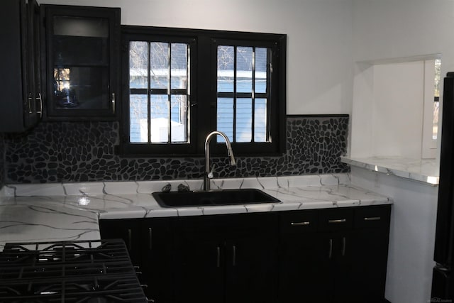 kitchen featuring refrigerator, sink, tasteful backsplash, light stone counters, and gas cooktop