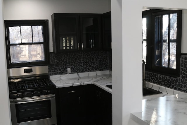 kitchen with gas stove, decorative backsplash, and light stone counters