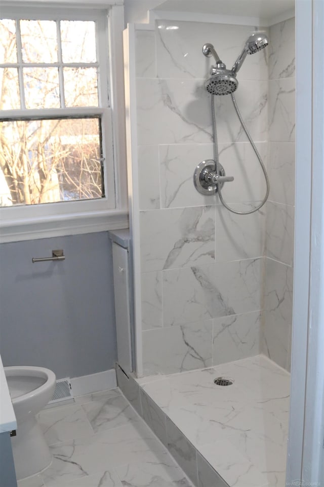 bathroom with a tile shower and toilet