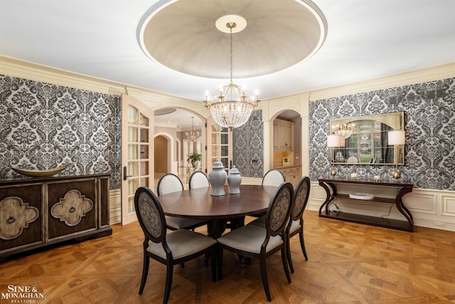 dining room featuring a tray ceiling, an inviting chandelier, and parquet flooring