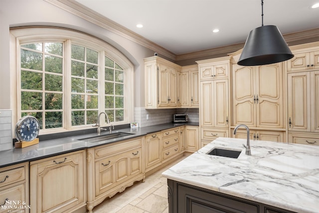 kitchen with pendant lighting, crown molding, sink, and dark stone counters