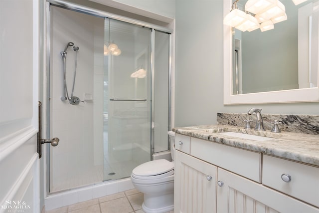 bathroom with tile patterned floors, vanity, a shower with shower door, and toilet