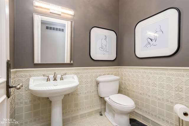 bathroom featuring tile patterned floors, toilet, tile walls, and sink