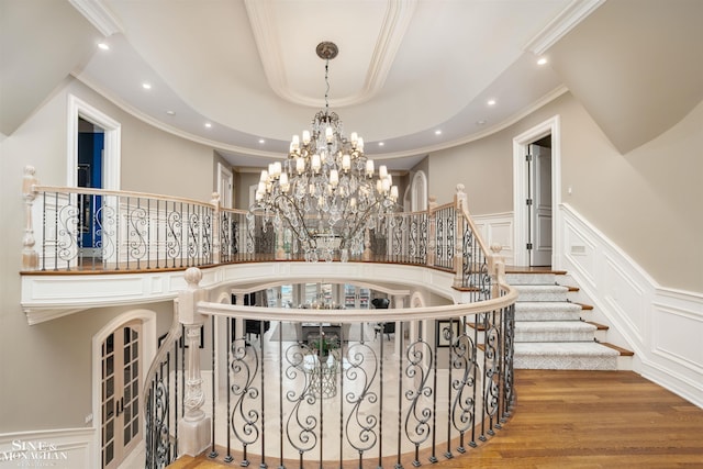 staircase featuring hardwood / wood-style flooring, crown molding, and an inviting chandelier