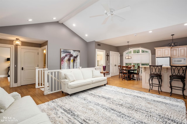 living room featuring beamed ceiling, ceiling fan with notable chandelier, high vaulted ceiling, and light hardwood / wood-style flooring