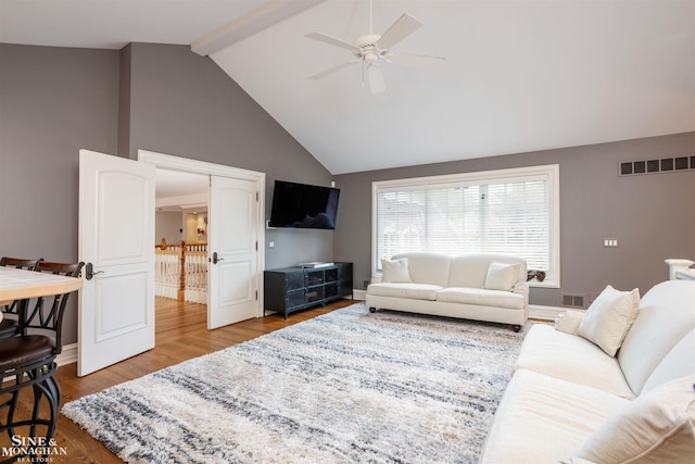 living room with beamed ceiling, ceiling fan, wood-type flooring, and high vaulted ceiling