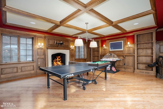 game room with coffered ceiling, beam ceiling, ornamental molding, and light hardwood / wood-style flooring