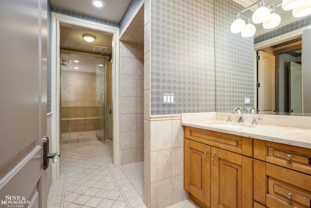 bathroom with tile patterned floors, a shower with door, vanity, and tile walls