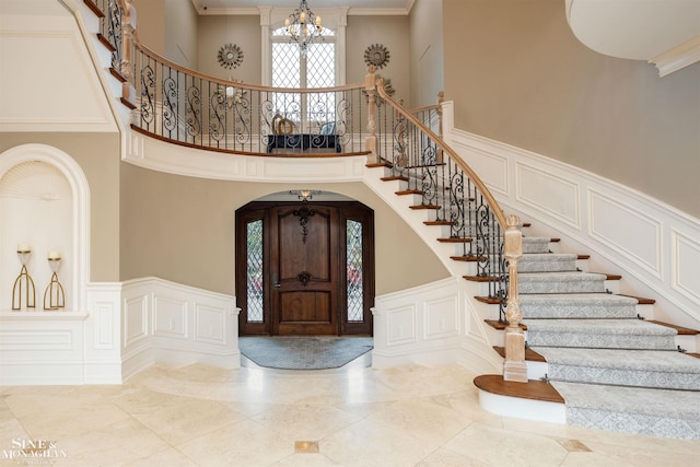 entrance foyer with crown molding, a towering ceiling, and a chandelier