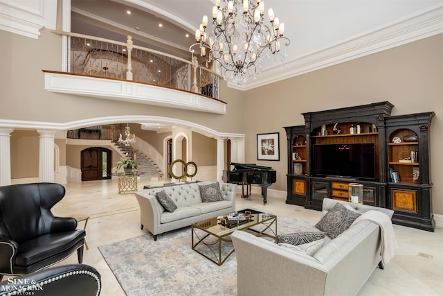 living room with a chandelier, a high ceiling, decorative columns, and ornamental molding