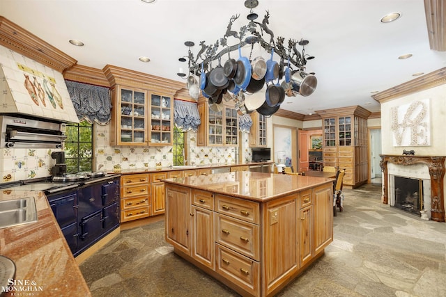 kitchen with light stone countertops, a center island, sink, decorative backsplash, and ornamental molding