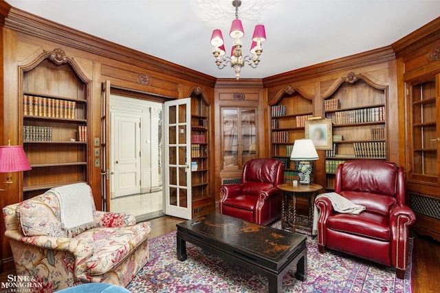 sitting room featuring built in shelves, hardwood / wood-style flooring, and an inviting chandelier