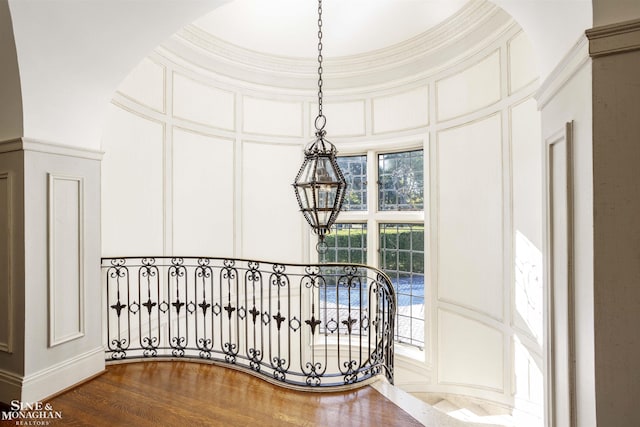 staircase featuring a chandelier, hardwood / wood-style floors, a healthy amount of sunlight, and a high ceiling