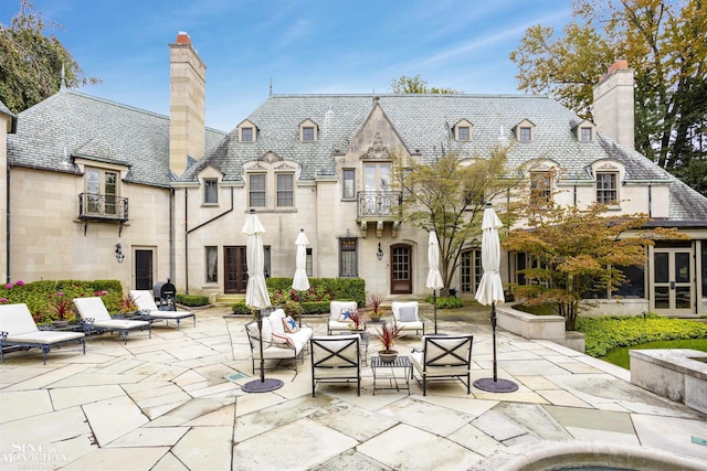 rear view of property featuring outdoor lounge area, a balcony, and a patio