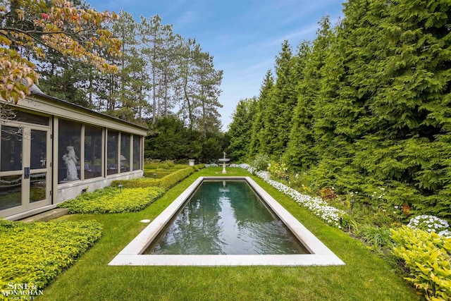 view of pool with a sunroom and a lawn