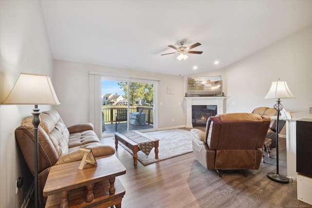 living room with hardwood / wood-style flooring, ceiling fan, and vaulted ceiling