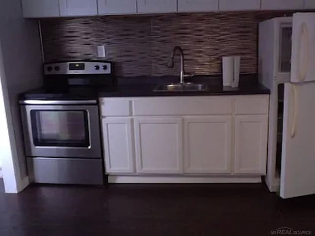 kitchen with electric range, sink, and white cabinets