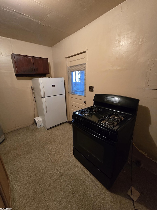 kitchen with black gas stove, white fridge, and dark brown cabinets