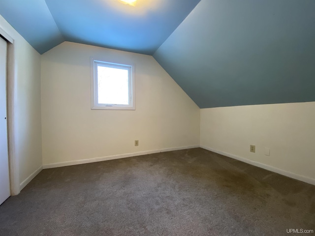 additional living space with dark carpet and vaulted ceiling