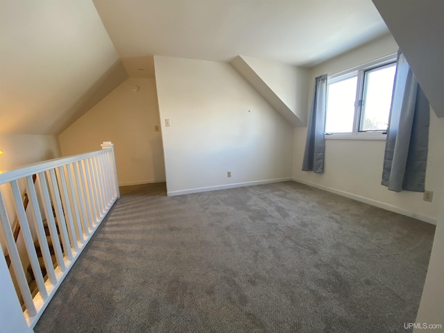 bonus room with lofted ceiling and dark colored carpet