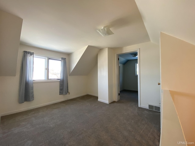 bonus room with dark colored carpet and vaulted ceiling