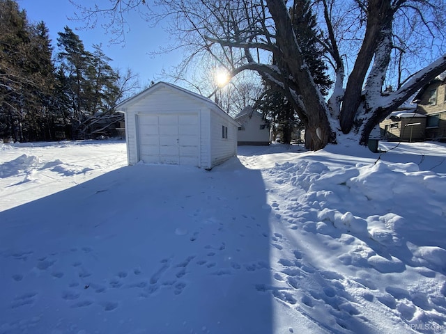 yard layered in snow with an outdoor structure and a garage