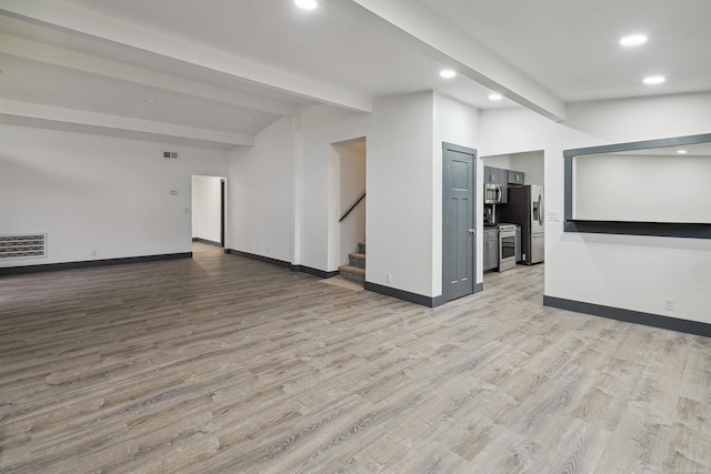 spare room featuring beamed ceiling and light hardwood / wood-style floors