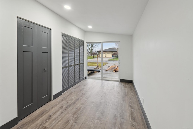 hallway with lofted ceiling and light wood-type flooring