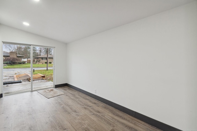 empty room with light hardwood / wood-style flooring and vaulted ceiling