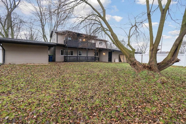 rear view of house featuring a balcony and a yard