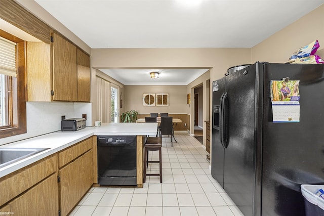 kitchen featuring a breakfast bar area, kitchen peninsula, sink, and black appliances