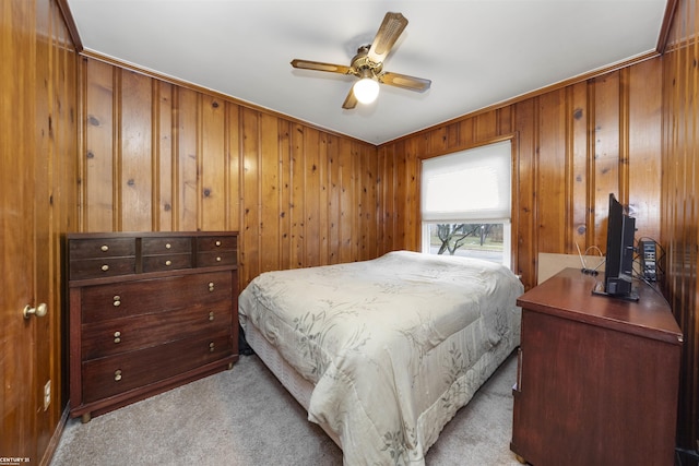 bedroom featuring ceiling fan, light colored carpet, wood walls, and ornamental molding