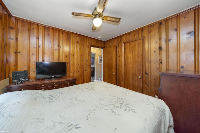 bedroom with ceiling fan and wooden walls